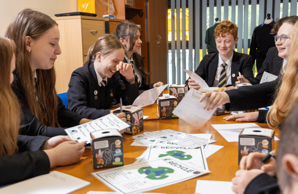 A group of high school students sat around a table with paperwork on it.
