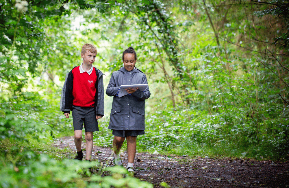 Two students walking through the woods.