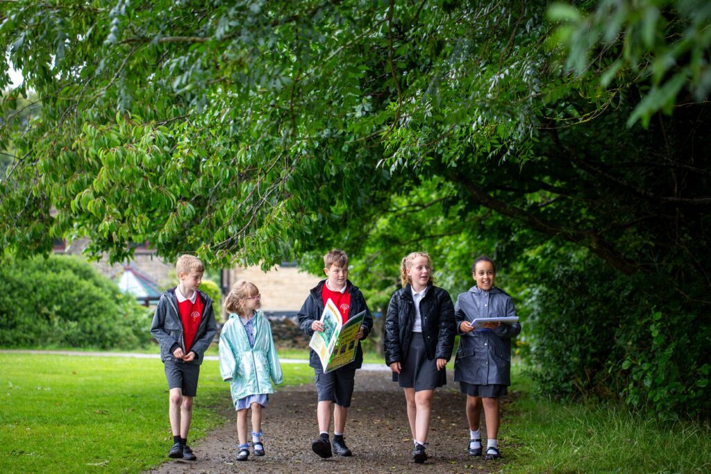 A group of five students walking through some woodland.