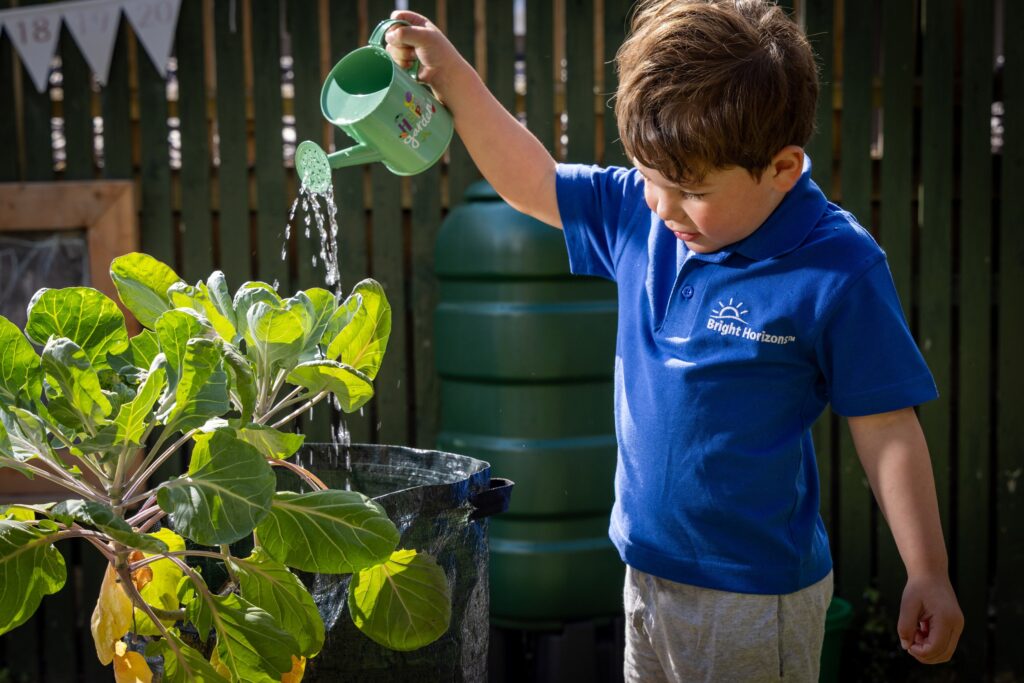 A young boy watering plants.