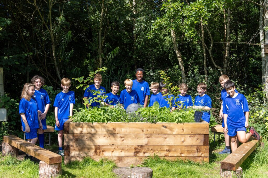A group of students stood around some raised beds.