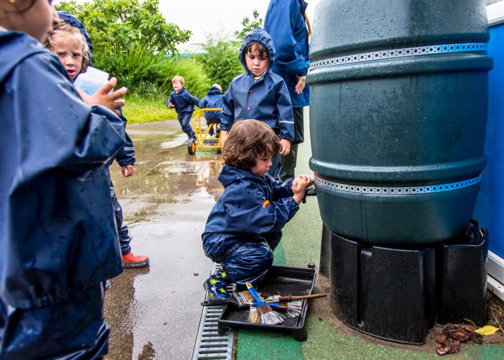 A group of children stood around a water butt.